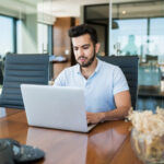 dedicated young businessman working laptop desk meeting room scaled.jpg