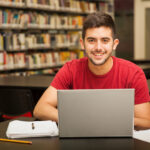 portrait attractive latin student doing some school work with laptop library scaled.jpg